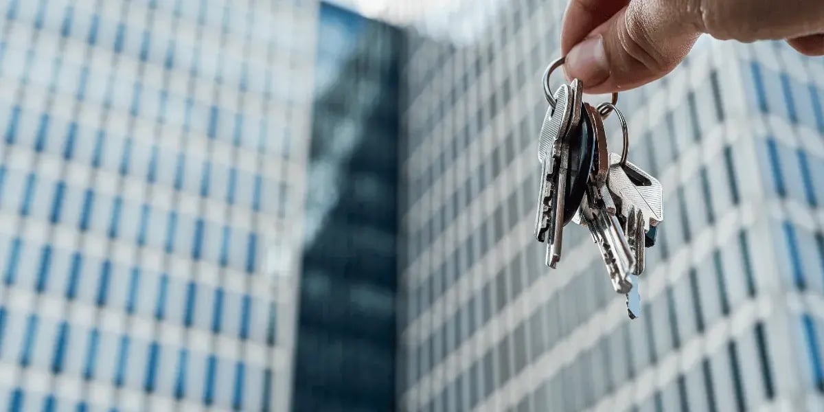 Man holding keys in front of a tall building